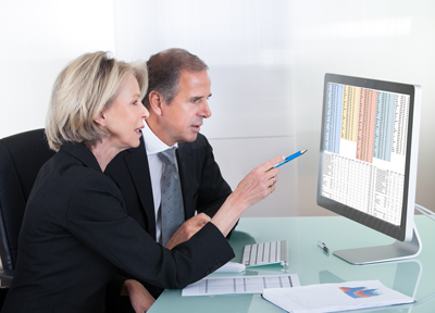 Happy Mature Businessman And Businesswoman Looking At Graph On Computer