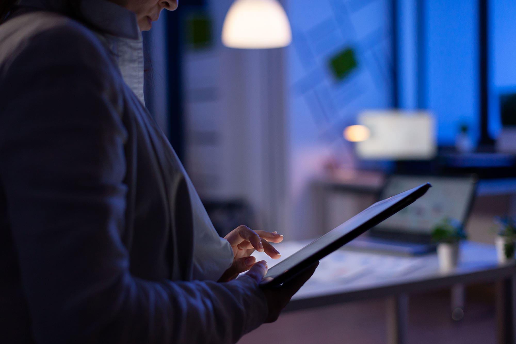 image of person going over numbers on tablet late night in the office